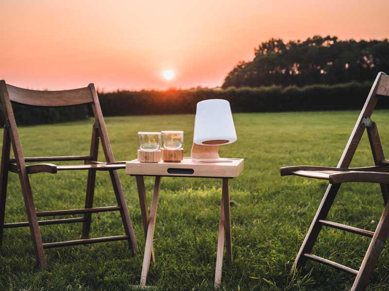 speakerlamp met tafels en stoelen in weiland met zonsondergang